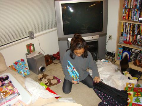 1989 Ford Bronco - A woman opens presents in a room with a large television and shelves full of media.
