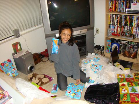 1989 Ford Bronco - A young girl smiles while holding a box of snacks amidst a pile of Christmas gifts and wrapping paper.