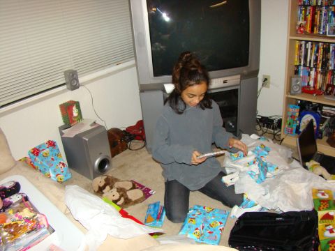 1989 Ford Bronco - A girl opens presents in a room with a large television and shelves filled with movies.
