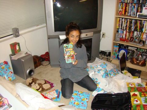 1989 Ford Bronco - A young girl holds up a toy in a room filled with Christmas gifts and wrapping paper.