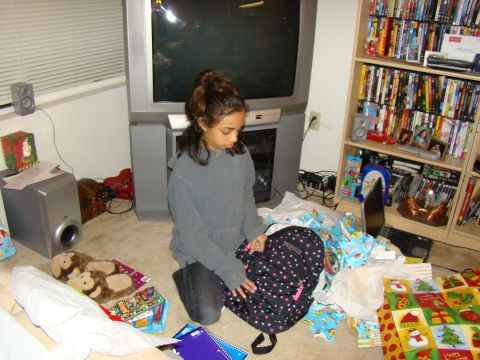 1989 Ford Bronco - A young girl is surrounded by discarded Christmas wrapping paper and gifts, holding a backpack.