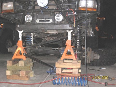 1994 Ford Bronco - Front suspension of a 1994 Ford Bronco being worked on, with jack stands and new springs visible.