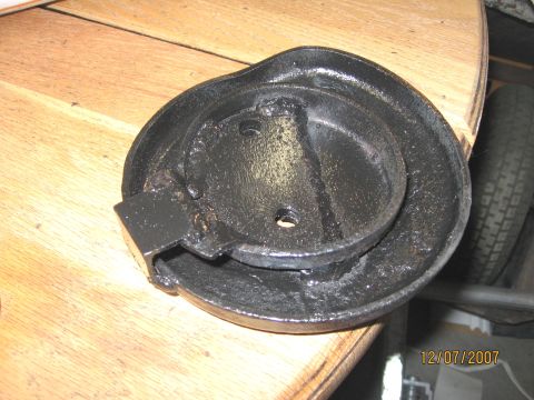 1994 Ford Bronco - A close-up view of a black metal component, possibly a brake drum or similar part, on a wooden table.
