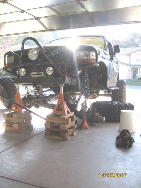 1994 Ford Bronco - This lifted pickup truck is undergoing maintenance, with its front suspension and wheels removed and supported by jack stands.