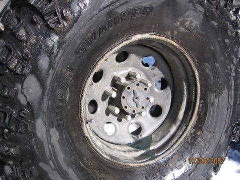 1994 Ford Bronco - A close-up view of a tire and wheel assembly, the brand name 'SWAMPER' on the tire sidewall.