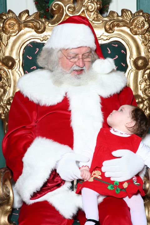 2000 Ford Crown Victoria - Santa Claus sits on a throne holding a baby girl dressed in red.
