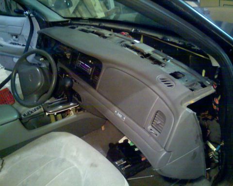 2000 Ford Crown Victoria - The dashboard of a car is partially disassembled, revealing its internal wiring and components.
