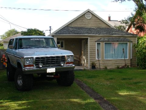 1978 Ford Bronco - Lifted 1978 Ford Bronco with large tires parked on a grassy lawn in front of a house.