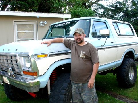 1978 Ford Bronco - A man poses with his lifted 1978 Ford Bronco, a two-tone paint scheme and off-road tires.