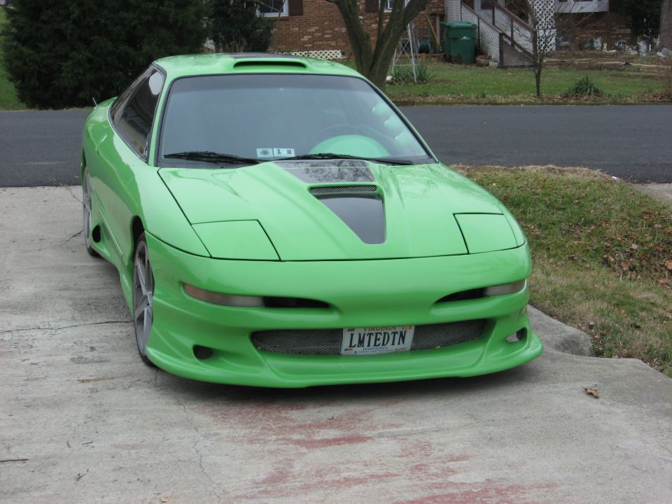 Green 1994 Ford Probe with custom body kit and hood scoop parked on a driveway
