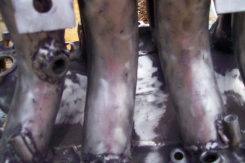 1988 Ford Bronco - Close-up of an engine intake manifold, showing its metallic tubes and some discoloration.