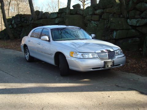 2002 Lincoln Town Car - This 2002 Lincoln Town Car is shown from a 3/4 front angle, parked outdoors with a stone wall in the background.