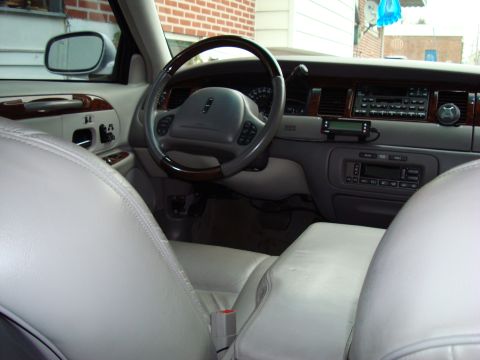 2002 Lincoln Town Car - The interior of a 2002 Lincoln Town Car features light-colored leather seats and wood trim accents on the dashboard and steering wheel.