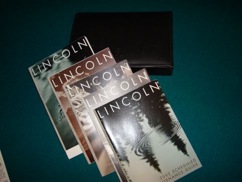 2002 Lincoln Town Car - A collection of Lincoln brochures and an owner's manual are displayed on a green surface.