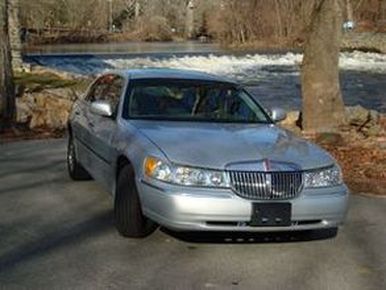 2002 Lincoln Town Car - A silver 2002 Lincoln Town Car is parked near a river with trees in the background.