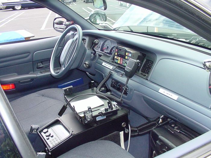 Interior of a 2001 Ford Crown Victoria police car, showing the dashboard, steering wheel, radio equipment, and center console
