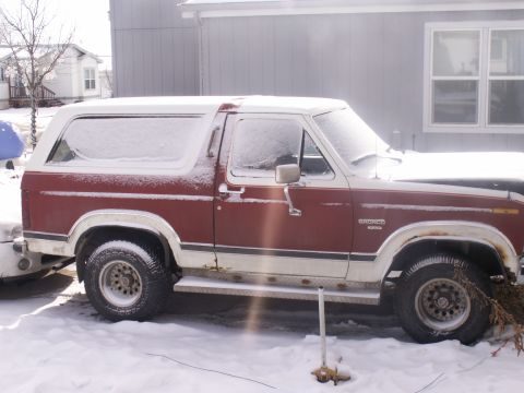 1984 Ford Bronco - This 1984 Ford Bronco is covered in snow, parked outside a house.