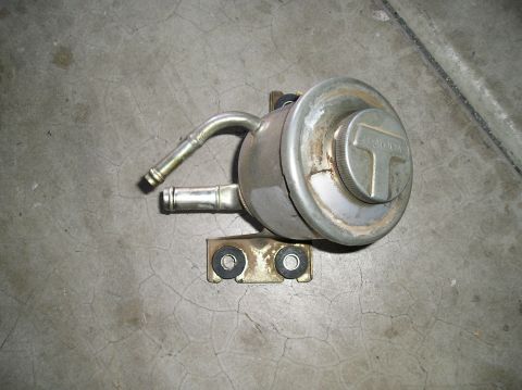 1986 Toyota Hilux - A metal vacuum actuator, identified by 'TOYOTA' text, is shown against a concrete surface.