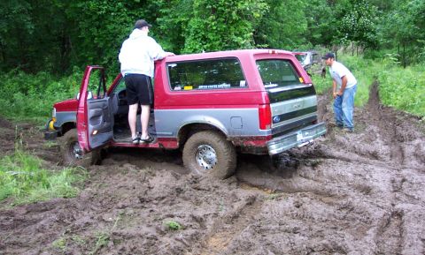 1995 Ford Bronco - This 1995 Ford Bronco is stuck in the mud, with one person standing in the open driver's door.