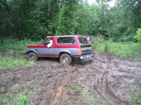 1995 Ford Bronco - This 1995 Ford Bronco navigates a muddy trail, its tires digging into the soft ground.