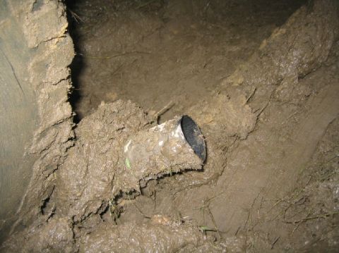1995 Ford Bronco - A pipe emerges from a muddy area, surrounded by dirt and grass.