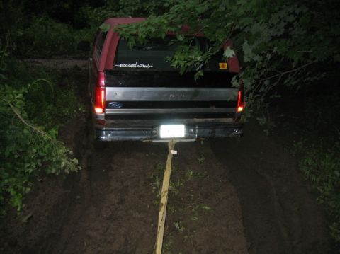 1995 Ford Bronco - This 1995 Ford Bronco is seen from the rear, stuck in a muddy trail with a tow strap attached.