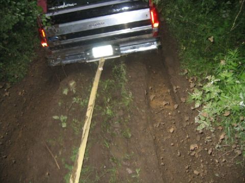 1995 Ford Bronco - Ford pickup truck is stuck in the mud, with a wooden plank propping up the rear bumper.