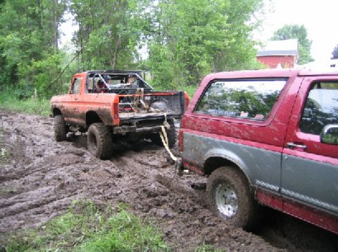 1995 Ford Bronco - Two off-road vehicles are stuck in thick mud, with one being towed.