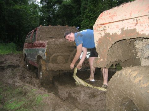 1995 Ford Bronco - Two off-road vehicles are stuck in deep mud, with a person attempting to free one of them.