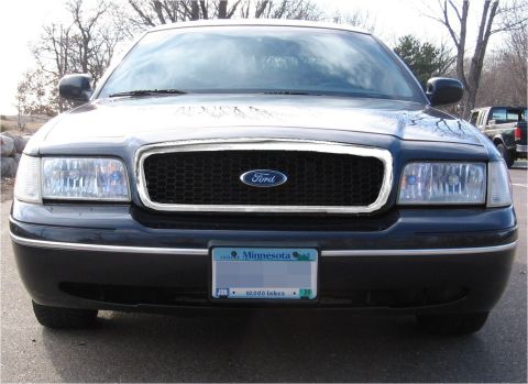 1999 Ford Crown Victoria - Front view of a black Ford Crown Victoria with a honeycomb grille and a Minnesota license plate.