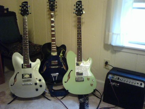 1995 Ford Bronco - A collection of three electric guitars, including white, black, and mint green models, are displayed with a black amplifier.