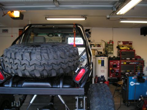 1986 Toyota Hilux - Off-road vehicle's rear view shows a large spare tire and a custom license plate in a garage setting.