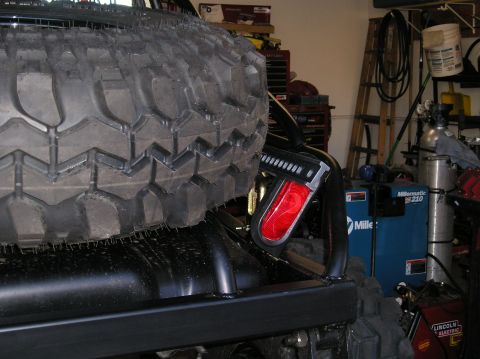 1986 Toyota Hilux - A close-up view of a spare tire and a red taillight mounted on the rear of a vehicle in a workshop.