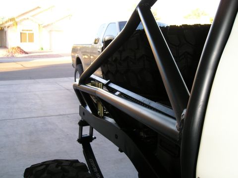 1986 Toyota Hilux - The rear of an off-road truck is visible, a spare tire and roll cage, with another truck parked behind it.