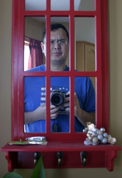 1994 Ford Bronco - Man takes a mirror selfie with a camera, reflected in a red-framed mirror.