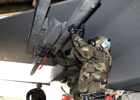 1994 Ford Bronco - Airmen in protective gear perform maintenance on an aircraft's wing, preparing a missile for deployment.