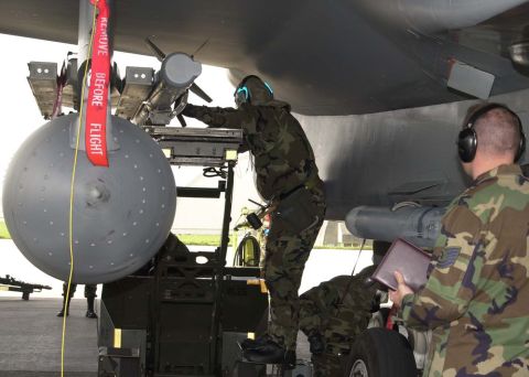 1994 Ford Bronco - Personnel conduct maintenance on aircraft ordnance, including a large bomb and a missile, under the wing of a plane.