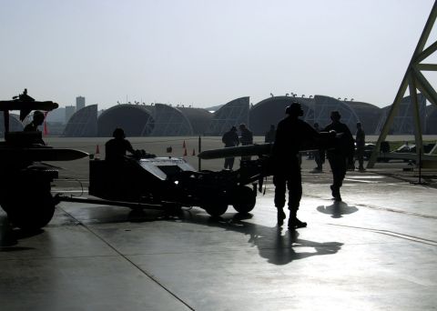 1994 Ford Bronco - Personnel are silhouetted against the bright sky as they move equipment on an airfield.