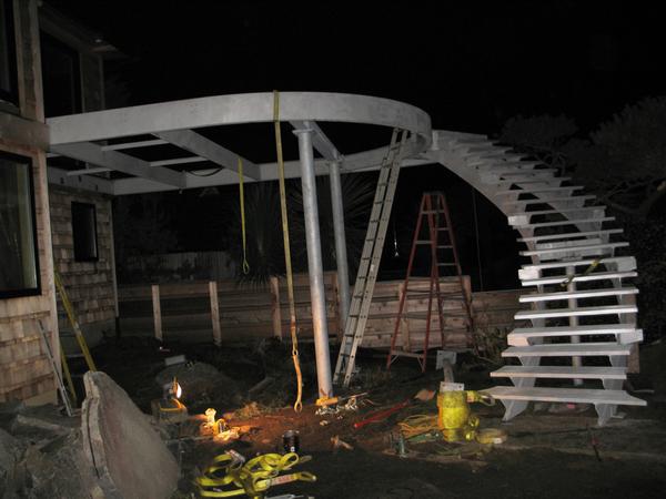 Construction scene at night with a curved staircase and ladders