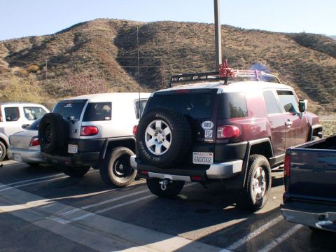 2007 Toyota FJ Cruiser - Two Toyota FJ Cruisers are parked side-by-side in a lot with a pickup truck to the right.