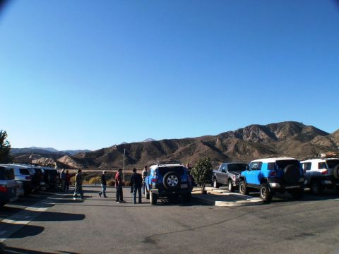 2007 Toyota FJ Cruiser - Several Toyota FJ Cruisers are parked in a lot with a mountainous backdrop under a clear blue sky.