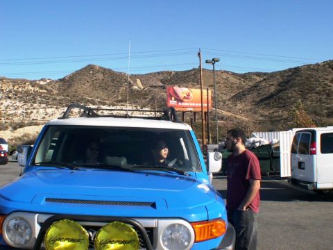 2007 Toyota FJ Cruiser - A blue Toyota FJ Cruiser is parked with people inside, while a man stands nearby. A white van is visible in the background.