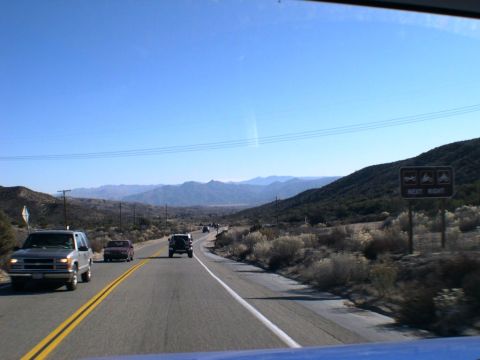 2007 Toyota FJ Cruiser - Vehicles travel along a two-lane highway through a mountainous desert landscape under a clear blue sky.
