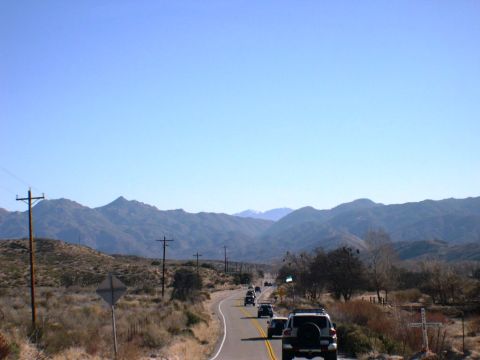 2007 Toyota FJ Cruiser - A convoy of SUVs travels along a winding road through a scenic desert landscape under a clear blue sky.