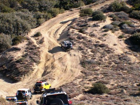 2007 Toyota FJ Cruiser - Multiple Toyota FJ Cruisers navigate a challenging off-road trail in a desert environment.