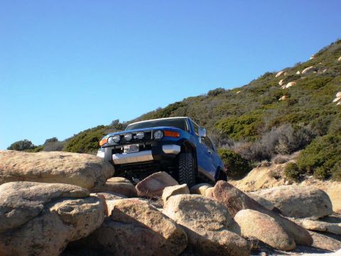 2007 Toyota FJ Cruiser - 2007 Toyota FJ Cruiser tackling a challenging rocky off-road path under a clear blue sky.