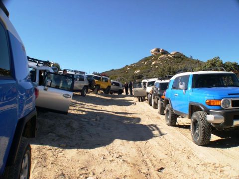 2007 Toyota FJ Cruiser - Multiple 2007 Toyota FJ Cruisers lined up on a dirt road during an off-road excursion.