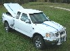 2003 Ford F-150 - A white pickup truck with a bed cap is parked on a grassy area.
