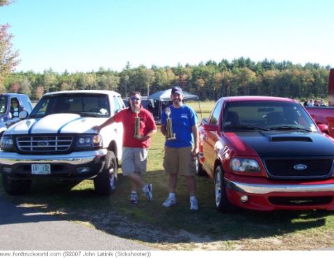 2003 Ford F-150 - Two men proudly display their trophies next to their respective Ford F-150 trucks at an outdoor event.