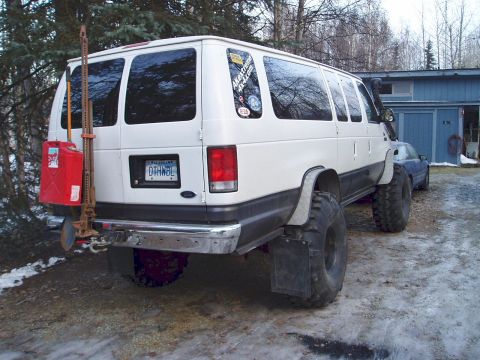 2000 Ford E350 - 3/4-rear view of a white lifted Ford extended-body van on oversized mud-terrain tires with a snorkel running up the A-pillar, parked on a s…
